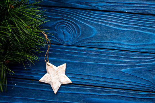 New Year decorations with christmas tree branche and star on blue wooden background top veiw mock up