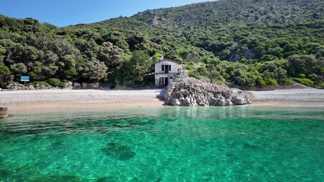 Crystal-clear Adriatic waters embrace the peaceful coastline of Sveti Ivan Beach on Cres Island, Croatia, where emerald-covered slopes descend toward a pebble cove dotted with anchored sailing boats.