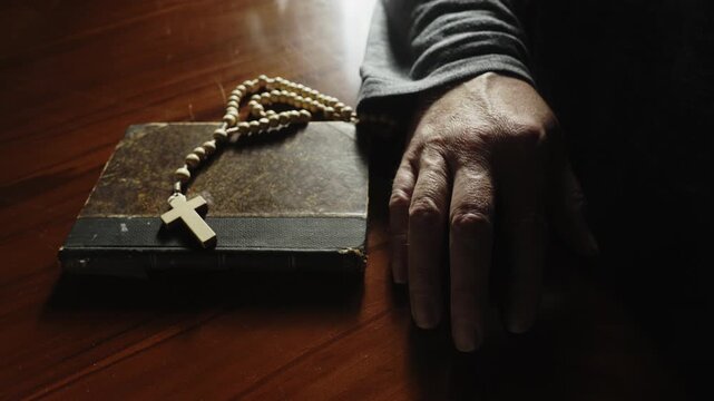 Close-up of hands pulling a prayer book and rosary closer before pushing them away, portraying spiritual conflict, doubt, inner turmoil, and a personal crisis of faith.