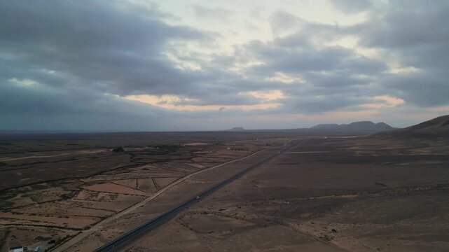 Aerial view of the arid landscape with a road stretching through the volcanic terrain near El Cotillo, Canary Islands, Spain.