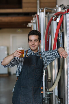 Portrait of confident young man holding beer glass at a brewery