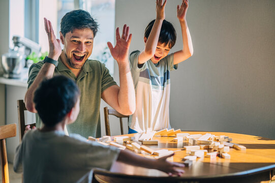Excited father and child playing a wooden block game at home