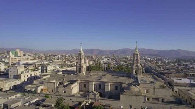 Aerial view of Arequipa Cathedral and historic city rooftops under a clear blue sky with mountains in the background in Arequipa, Arequipa, Peru.