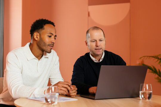 Mature businessman having discussion with colleague over laptop in office