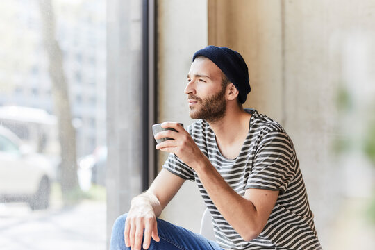 Young man holding coffee cup at the window