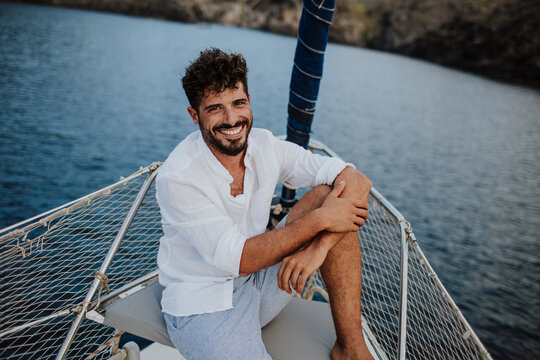 Smiling man relaxing on a sailboat deck during summer vacation