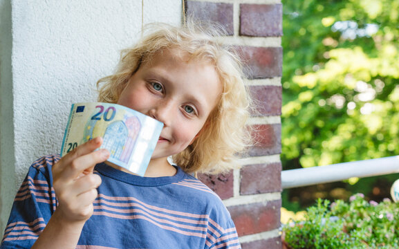 Smiling boy showing currency near wall