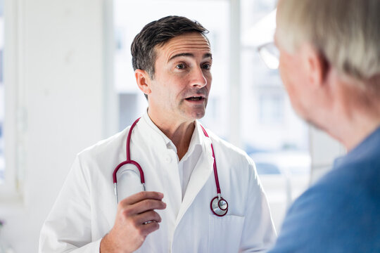 Portrait of doctor and talking to patient in medical practice