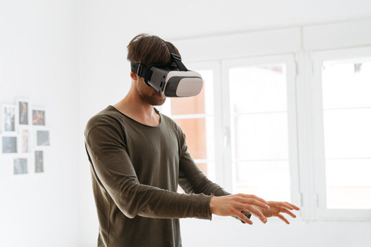 Young man wearing virtual reality glasses at home