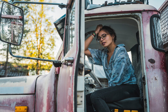 Young woman sitting in cabin of a broken vintage truck