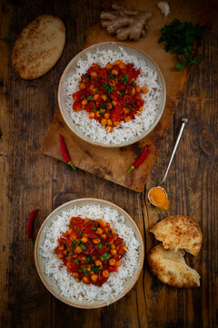 Two bowls feature Indian chickpea curry with rice and naan bread