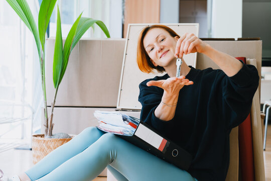 Smiling woman holds key to new apartment during relocation