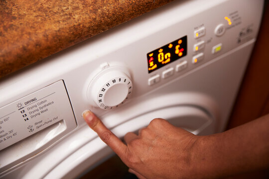 Woman operating washing machine at home