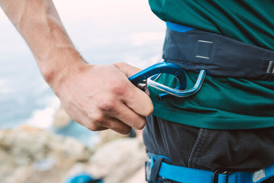Close-up of climber placing a carabiner in his climbing harness