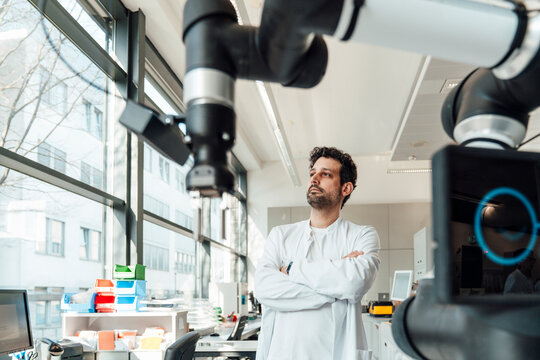 Scientist looking at robotic arm in modern medical laboratory