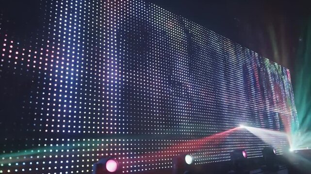 A large LED screen displaying colorful lights and laser beams in a dark environment.