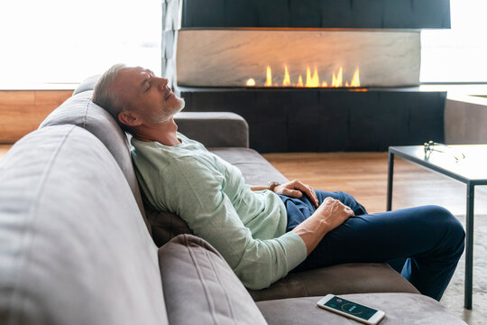 Man with eyes closed resting on sofa at home
