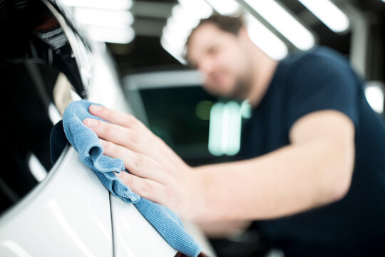 Close-up of man working in modern car factory wiping finished car
