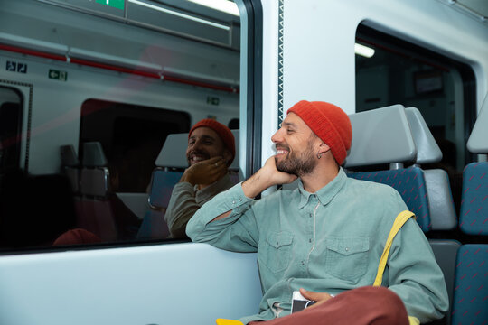 Smiling man wearing a beanie rides the subway in Barcelona