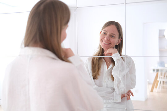 Smiling employee looking in the mirror at the casual office