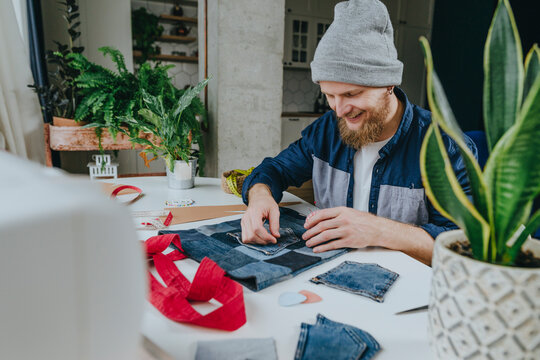 Happy fashion designer stitching pocket on shopping bag in workshop