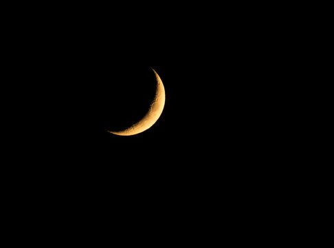 Waxing Crescent moon glowing against pitch black sky at night