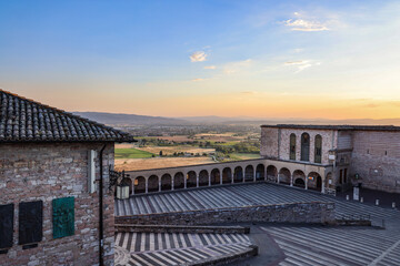 Obraz premium Sunset View of Basilica of Saint Francis Square and Umbrian Plain. Medieval Architecture and Italian Countryside Panorama, Assisi, Italy