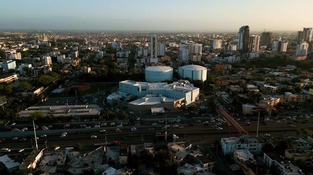 Aerial view of Hospital Dr. Dario Contreras surrounded by urban infrastructure, large water tanks, and a busy highway in Santo Domingo Este, Santo Domingo, Dominican Republic.