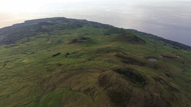 Aerial view of Pico Island volcanic landscape with lush green craters and rolling hills in Pico, Azores, Portugal.