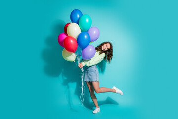 Obraz premium Happy young woman holding colorful balloons in a playful studio portrait celebrating a party moment