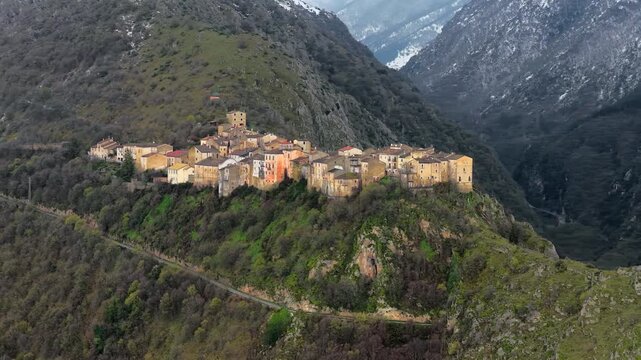 Aerial view of the historic stone village of Anversa degli Abruzzi nestled on a green hillside surrounded by mountains in Anversa degli Abruzzi, Abruzzo, Italy.