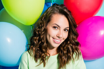 Obraz premium Smiling young woman with colorful balloons, curly hair and casual green top celebrating a cheerful party or birthday portrait conveying joy and positive lifestyle energy