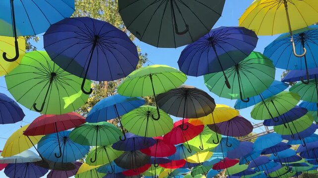 Multicolored umbrellas overlap across an outdoor display, festive decoration, summer leisure, playful pattern, holiday decoration.