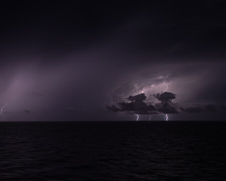 Stormy weather and climate change, lightning strikes over dark ocean at night