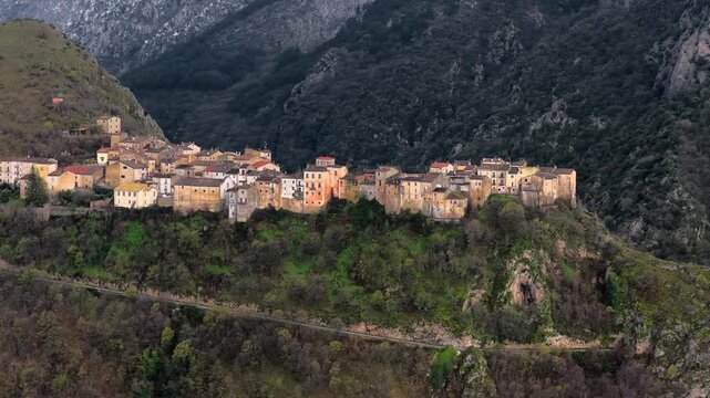 Aerial view of historic village perched on a rocky cliff surrounded by lush mountains and dense forests, Anversa degli Abruzzi, Abruzzo, Italy.