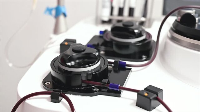 Close-up footage of the spinning centrifuge and tubing of an apheresis machine during a plasma donation at a medical clinic, the device in motion.