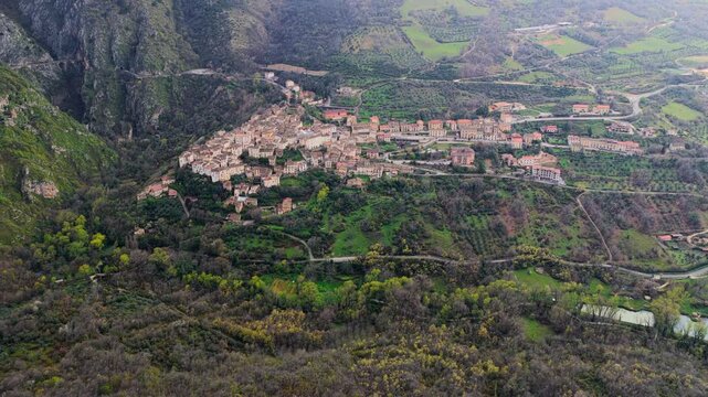 Aerial view of the historic village of Anversa degli Abruzzi nestled in a lush valley surrounded by green hills and rocky terrain in Anversa degli Abruzzi, Abruzzo, Italy.
