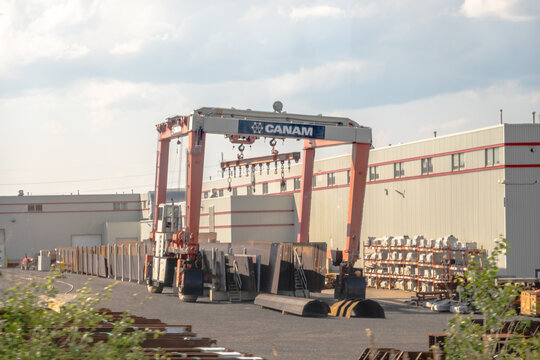 Montreal, Quebec, Canada. July 28, 2026. Wide angle view of Canam gantry crane moving heavy steel plates at industrial manufacturing plant.