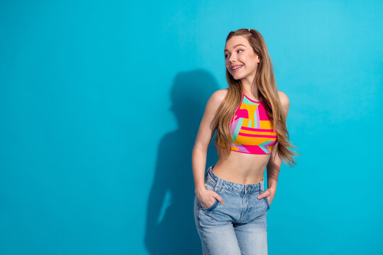 Lifestyle portrait of a young woman in colorful top against blue backdrop exuding happiness and stylish charm
