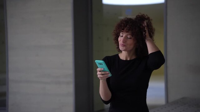 A cheerful and happy woman actively interacting with her smartphone in a modern workspace