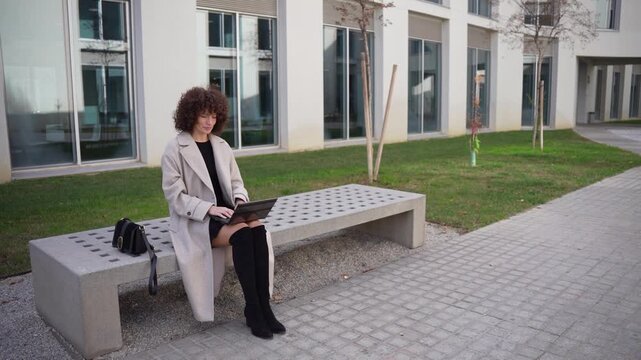 A Young Woman Sitting Outdoors Using a Laptop in a Stylish and Modern Courtyard Setting
