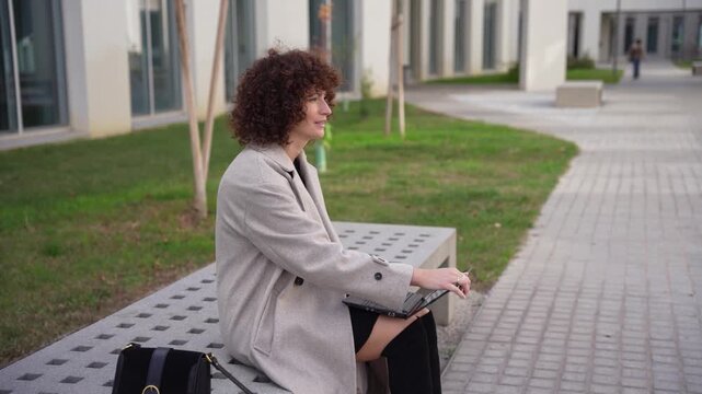 A Professional Woman Diligently Working Outdoors on Her Laptop Amidst a Scenic Setting