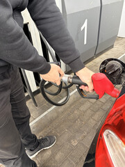Close-up of a person refueling a black car with a red nozzle at a gas station. Refueling a car © Vovmar