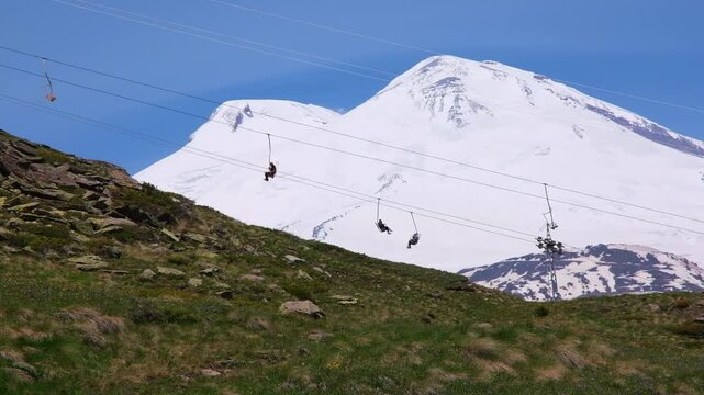 People sitting on a chairlift with Mount Elbrus in the background, Elbrus, Russia