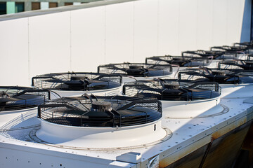 Rows of air conditioning units on the roof of building. Large cooling fans installed on a rooftop...