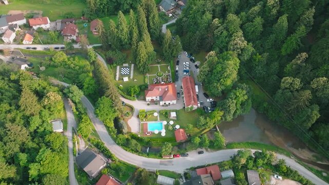 Aerial view of Kurija Hamor surrounded by lush forest, a swimming pool, and a winding road in Samobor, Zagrebacka zupanija, Croatia.