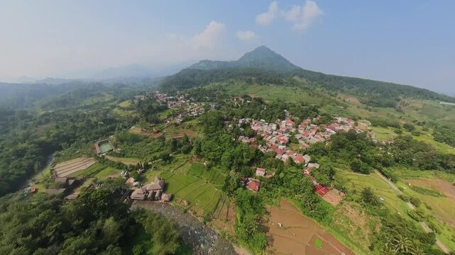 Aerial view of the lush landscape and village near Sentul with terraced fields and a winding river in Babakan Madang, West Java, Indonesia.