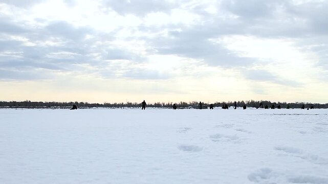 Fishermen on the snow-covered ice of the river on a winter day