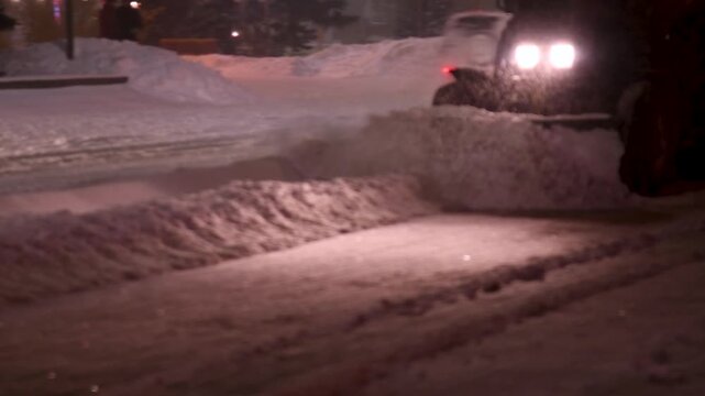 Large snow tractor at work on the evening streets of the city