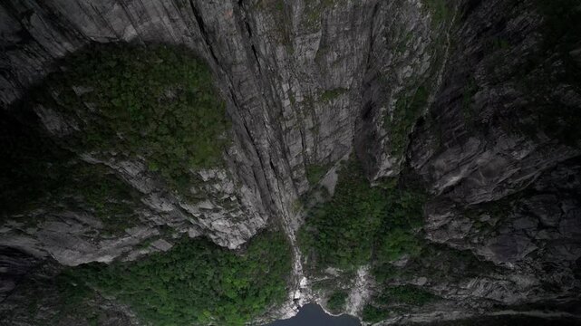 Aerial view of the steep rocky cliffs of Pulpit Rock with lush green vegetation and deep shadows in Strand, Rogaland, Norway.